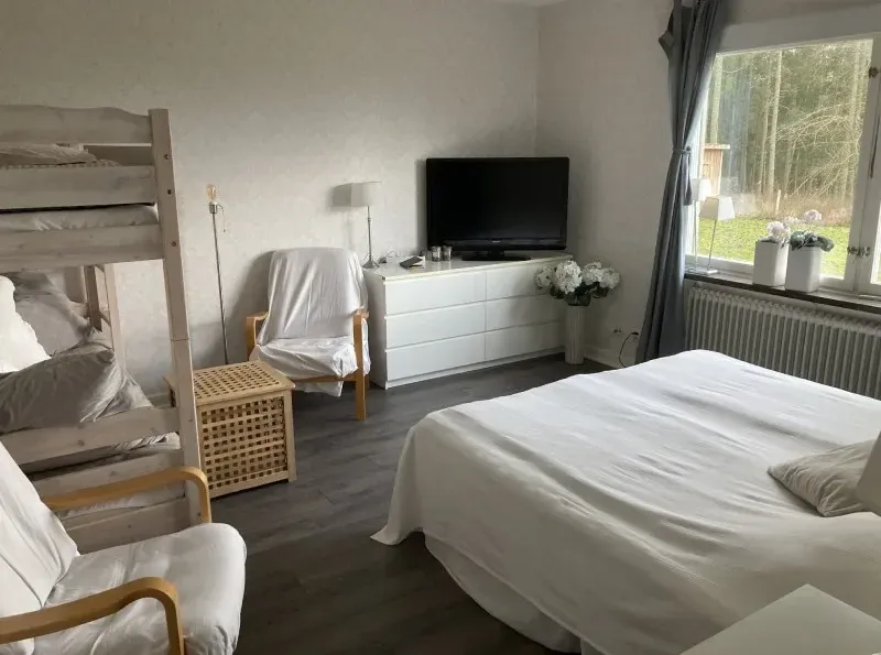 Ljust rum med dubbelsäng, våningssäng och TV