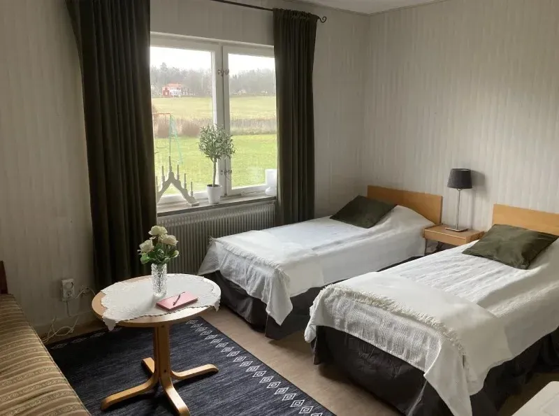 Rum med två enkelsängar, soffa och litet bord vid fönstret