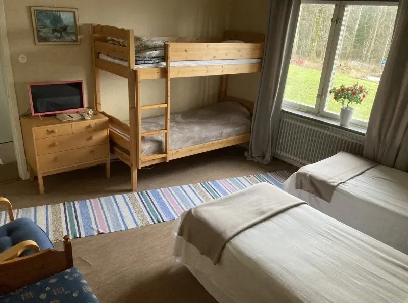Rum med våningssäng, två enkelsängar, byrå och TV